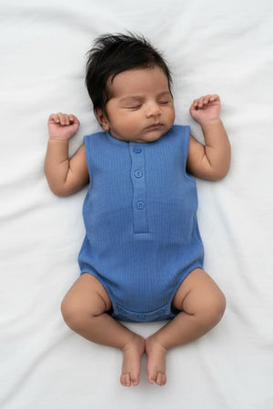 Baby wearing a blue onesie lying on a white surface