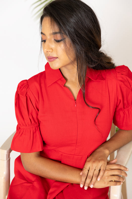 a woman in a red shirt is sitting on a chair 